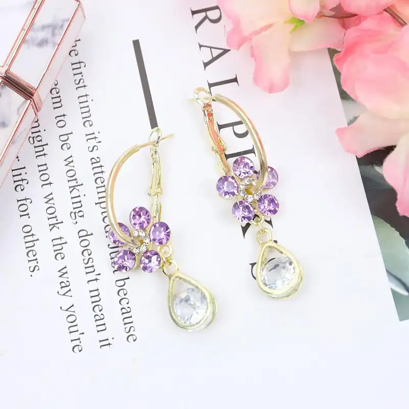 Beautiful gold earrings with purple gemstones and teardrop clear stones, perfect for elegant occasions and jewelry lovers.
