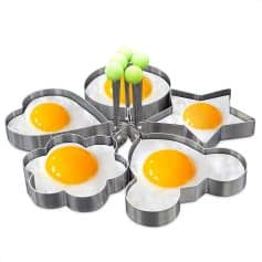 Egg molds for breakfast in flower, star, and heart shapes with eggs ready to cook, perfect for creative cooking and meal presentation.