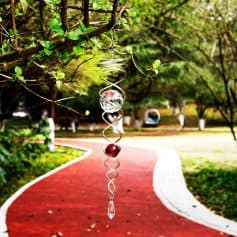 Decorative sun catcher, crystal wind chime hanging from tree branch, outdoor garden decor, reflecting sunlight, adds aesthetic appeal to outdoor spaces, perfect for yard, patio, or balcony.