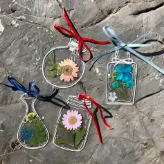 Colorful glass flowers and leaves inside transparent decorative frames with ribbons.