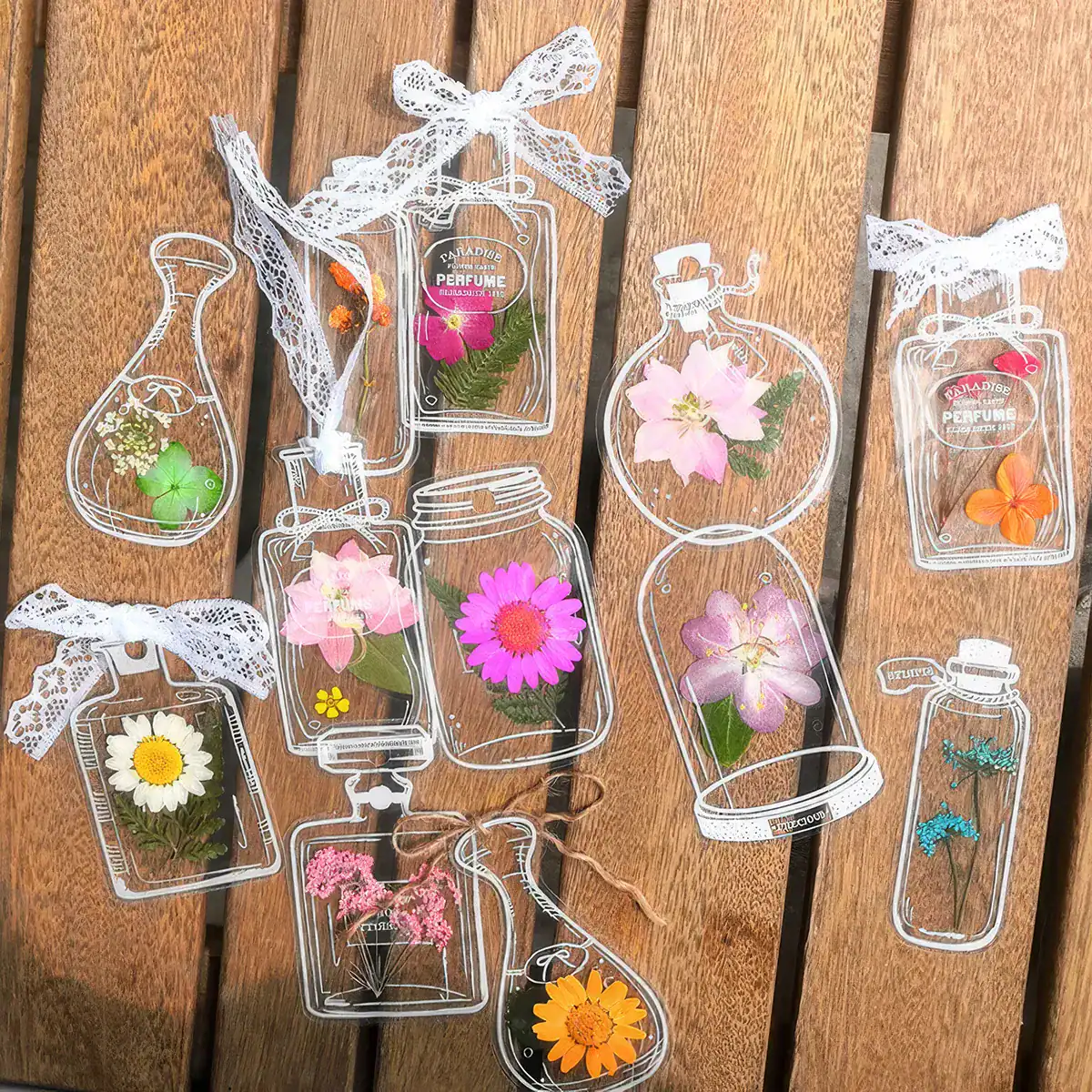 Bright floral perfume bottle ornaments with pink, yellow, purple, and orange flowers, decorative lace bows, ideal for beauty and fragrance stores.