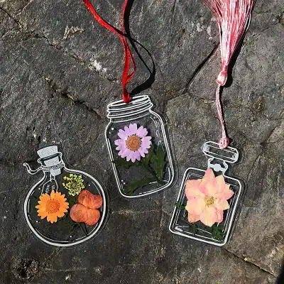 Decorative transparent glass flower containers featuring colorful flowers and hanging ribbons, ideal for home or office decoration and floral arrangements.