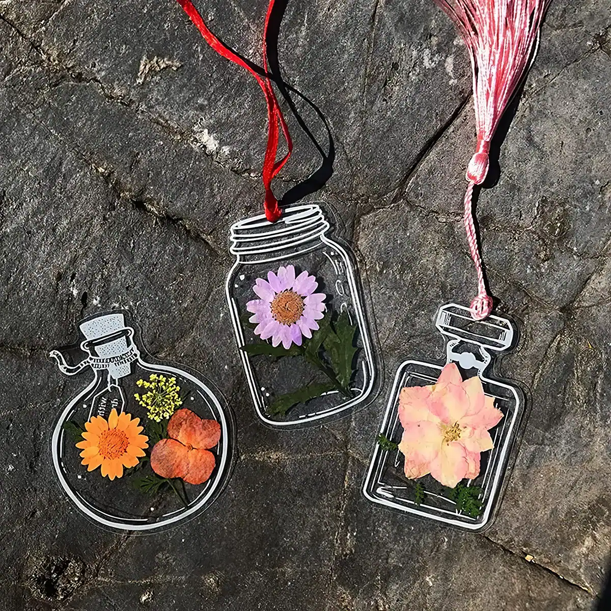 Decorative transparent glass flower containers featuring colorful flowers and hanging ribbons, ideal for home or office decoration and floral arrangements.