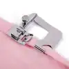 Close-up of a metal sewing machine hook guiding pink fabric for precise stitching, ideal for clothing, crafts, and upholstery sewing projects.