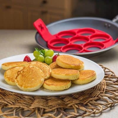Delicious homemade pancakes served with fresh grapes and strawberries, perfect for a hearty breakfast or brunch. A delightful plate showcasing comfort food with a touch of elegance.