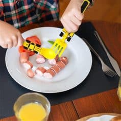 Child's playful meal with toy utensils and assorted mini sausages on a white plate, emphasizing nutritious and fun food choices for children.