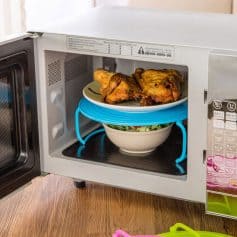 Alt text: Microwave oven with cooked chicken on a plate and a salad in a bowl inside, showcasing food reheating and cooking at Monalisa Medical Store.