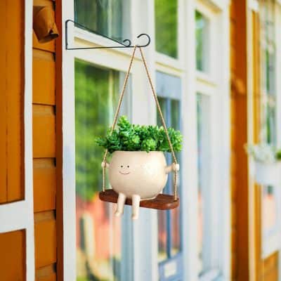 Adorable smiling plant pot hanging on porch with lush green plant for home garden decor. Perfect for enhancing your indoor or outdoor space.
