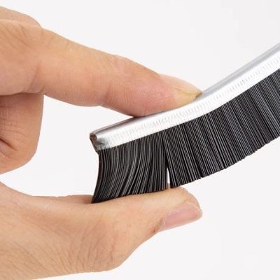 Close-up of a hand holding a false eyelash applicator tool with synthetic lashes, used for easy eyelash extension and eyelash application at the Monalisa Store.