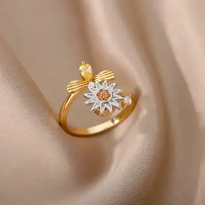 Gold and silver-tone ring featuring a daisy flower with orange stones and a bee motif, perfect for women's jewelry collection.