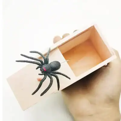 A black spider Halloween decoration with red eyes, placed on an open wooden box, perfect for spooky Halloween home decor or party setups.