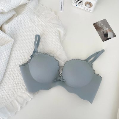 Elegant light gray bra with lace details displayed on a cozy white bed, highlighting premium lingerie and stylish accessories at Monalisa Store.