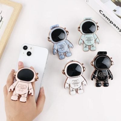 Adorable astronaut phone holder with a large black screen face, designed to attach securely to smartphones, making it easy to carry around and use hands-free.