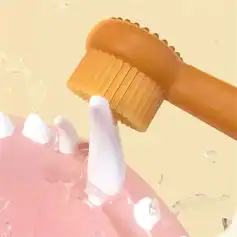 Alt text: Close-up of a facial cleansing brush with a wooden handle and silicone bristles being used on skincare skin.