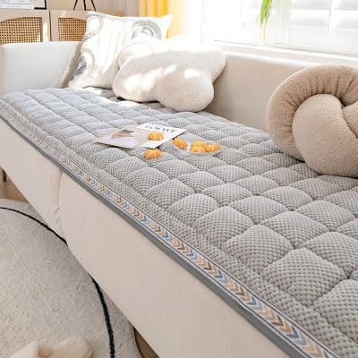 Luxurious mattress on a white sofa with plush pillows, cozy blanket, and natural lighting, showcasing premium sleep essentials and comfort products at Monalisa Store for optimal eye health and sleep quality development.