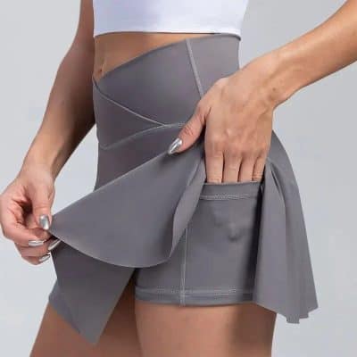 High-waisted grey athletic skirt with built-in shorts and secure pocket, perfect for yoga, Pilates, and activewear. Elegant design combines style and functionality for active women.