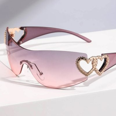 Fashionable pink gradient sunglasses with heart-shaped metallic accents, ideal for women’s eyewear and sun protection.