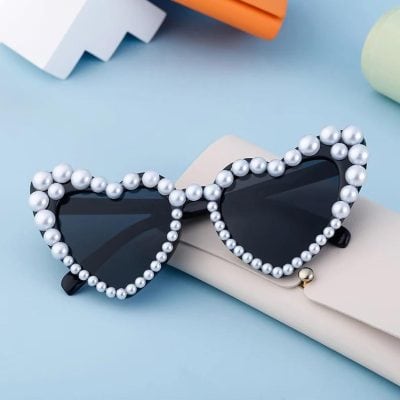 Stylish heart-shaped sunglasses adorned with pearls, perfect for fashion-forward women looking to make a statement with unique eyewear.