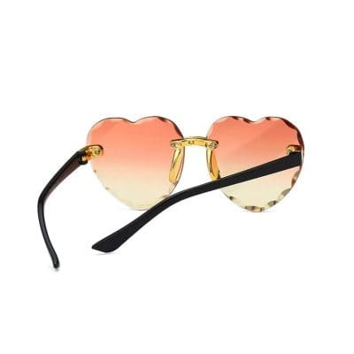 Stylish heart-shaped sunglasses with gradient pink lenses, gold accents, and black temples, perfect for fashion-forward eye protection and UV safety.