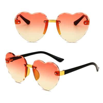 Bright heart-shaped sunglasses with gradient pink and yellow lenses, gold nose bridge, and black temple arms, ideal for trendy summer accessories, outdoor fashion, and stylish sun protection. Perfect for adding a playful and chic touch to any outfit.