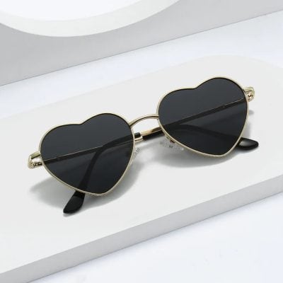 Heart-shaped sunglasses with dark lenses and gold frame, perfect for trendy eyewear fashion and sun protection. Unique design suitable for fashion-forward women.