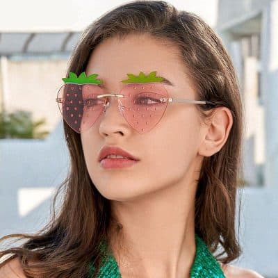 Playful strawberry-shaped sunglasses with pink lenses and green leaf details, perfect for stylish summer wear.