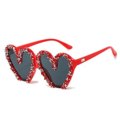 Decorative heart-shaped sunglasses with red frames and glitter accents offer a fashionable look, ideal for sunny days and special occasions. Available at Monalisa Medical, these trendy shades combine style and function for eyewear enthusiasts.