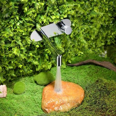 Bright, shiny outdoor garden faucet with water stream, surrounded by vibrant green plants and natural mossy ground cover.