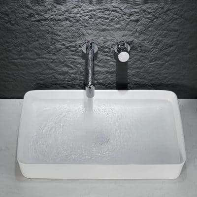 Ceramic sink with chrome tap and water flow, suitable for medical or clinical environments, clean and sleek design.