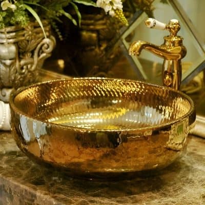 Golden bathroom sink with faucet, crafted with a shiny metallic finish for luxurious bathroom or vanity decor, perfect for modern and elegant interiors.