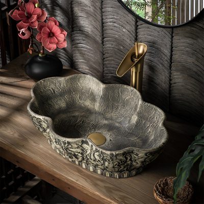 Sophisticated marble vessel sink with gold faucet, stylish bathroom accessories, and vibrant flowers for modern spa or wellness center.