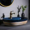 Luxury bathroom vanity with stylish blue and striped ceramic basin, brass faucet, and minimalist decor for premium interior design.