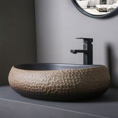 Crafted with textured, natural stone material and a sleek black faucet, this modern bathroom sink combines style and functionality for a luxurious look.