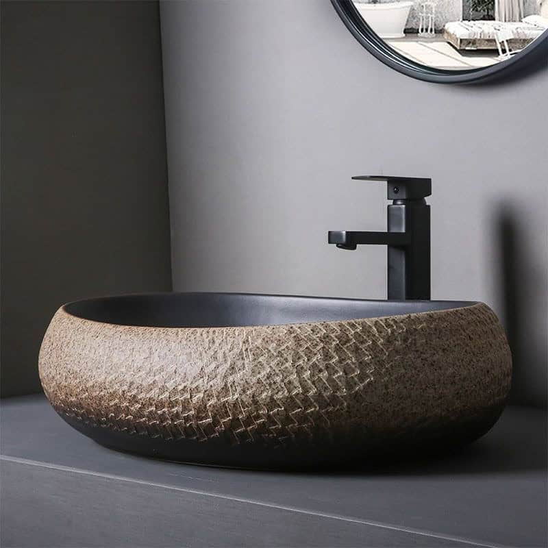 Crafted with textured, natural stone material and a sleek black faucet, this modern bathroom sink combines style and functionality for a luxurious look.