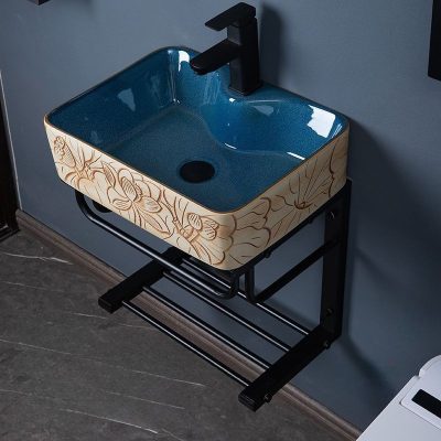 Stylish blue ceramic bathroom sink featuring detailed wood floral carving, mounted on a black metal frame for modern bathroom decor. Perfect for enhancing aesthetic appeal and functionality.