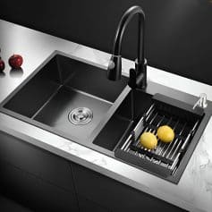 A modern black kitchen sink with faucet and drainboard, featuring a minimalist design, perfect for contemporary kitchens. Includes lemons and cherries on a marble countertop.