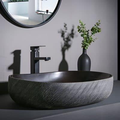 A stylish black vessel sink with black faucet and minimalist decor, including a matte black vase with green foliage, displayed in a modern bathroom setting at Monalisa Medical Store.