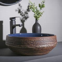 Stylish modern ceramic sink featuring a textured, layered exterior and sleek faucet, perfect for enhancing the aesthetics of any bathroom or spa space.