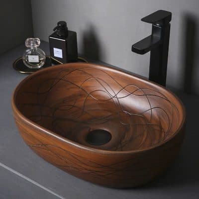 Luxury wooden sink with artistic engraved design for modern bathrooms. Crafted from high-quality wood with a sleek black faucet for stylish, functional bathroom decor.