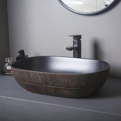 Stylish black and bronze oval vessel sink with modern black faucet, perfect for opt bathroom vanity setup and enhancing interior decor.
