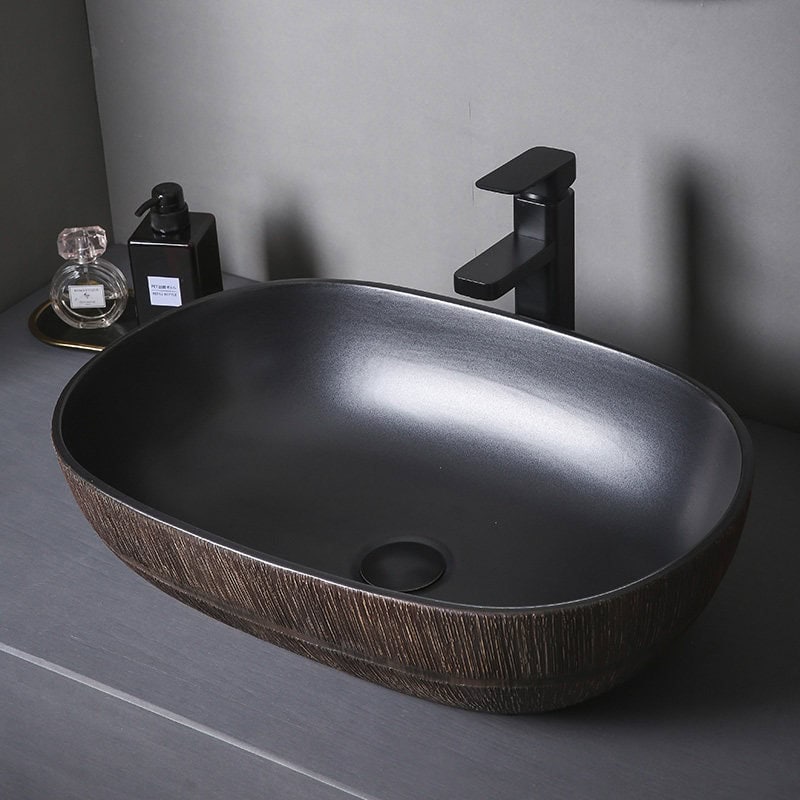 Black oval bathroom sink with wood-textured exterior and modern black faucet. Perfect for stylish, functional bathroom decor.