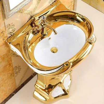 Shiny gold bathroom sink with ornate pedestal and classic faucet, perfect for luxurious bathroom interiors, combining style and functionality.