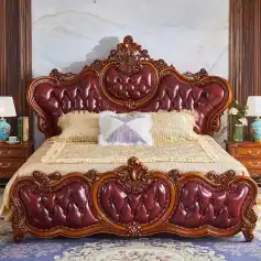 Luxurious carved wooden bedroom furniture with deep red leather upholstery, intricate detailing, and matching bedside tables, creating a regal and classic bedroom ambiance.