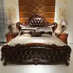 Elegant dark leather and wood queen-size bed with intricate carvings, tufted headboard, and classic design for upscale bedroom decor.