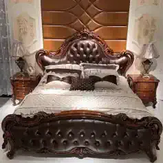 Luxurious leather-upholstered bed with ornate wooden carvings in classic style, paired with matching nightstands and elegant lamps, perfect for sophisticated bedroom decor.