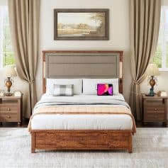 Image of a stylish bedroom featuring a wooden bed frame, plush bedding, bedside tables with lamps, framed artwork, and large windows with beige curtains, creating a cozy and sophisticated atmosphere.