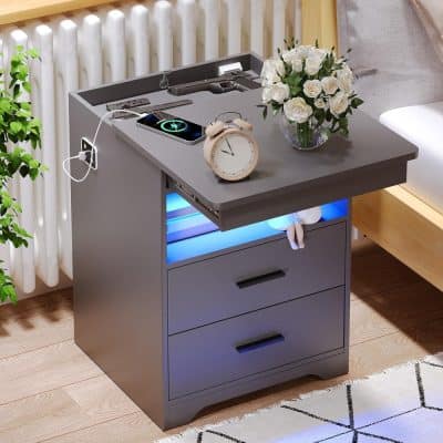 Elegant gray nightstand with drawers, USB port, alarm clock, gun replica, smartphone, and decorative flower vase for effective space management in opt and eye care clinics.