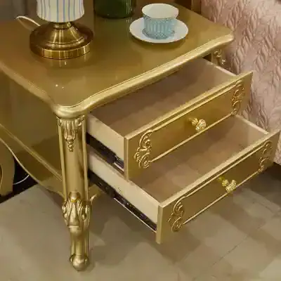 Luxury gold-colored nightstand with ornate drawer handles, intricate carved details, and spacious storage drawers, perfect for bedroom decor.