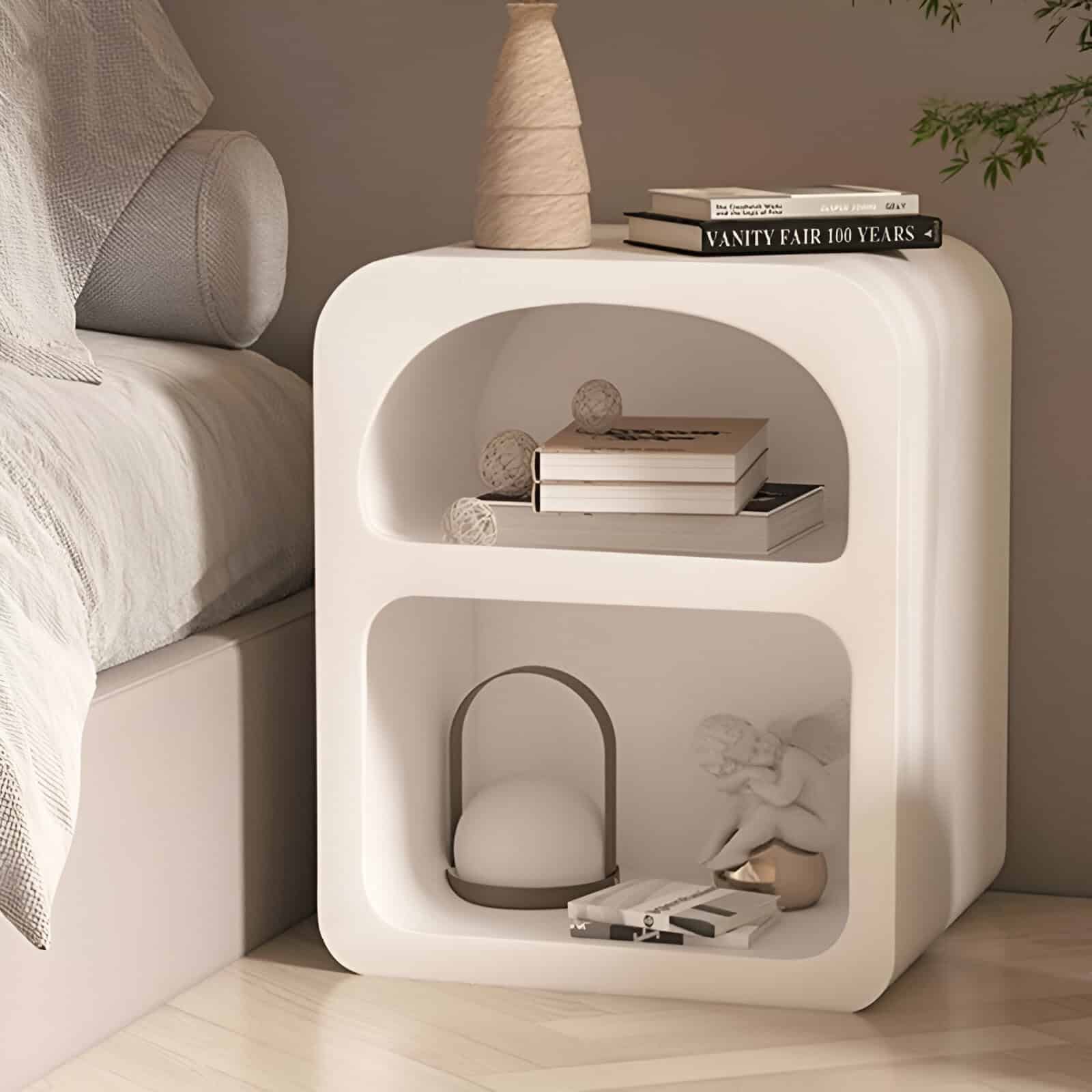 Versatile and elegant white nightstand featuring rounded edges and open shelving, perfect for bedroom decor, displaying books and ornaments for a contemporary look.