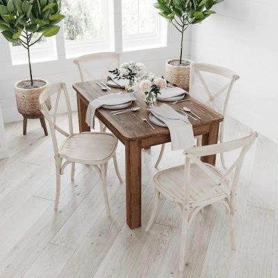 Stylish wooden dining table with white chairs, adorned with fresh flowers, in a bright, modern room featuring potted greenery for a cozy dining ambiance.